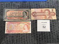 Three vintage Canadian $2 bills displayed on a gray textured background.