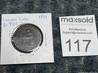 Obverse side close-up showing the seated figure clearly and the token's identification on the holder.