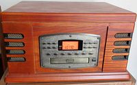 Front view of the Crosley audio unit showing wooden cabinet finish, radio LCD screen, and control buttons