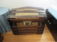 Front view of the wooden dome top trunk with oak bands and metal hardware.