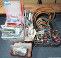 Wide view of embroidery supplies showing wooden hoops, fabric, kits, and floss storage containers.