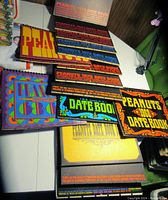 Photo showing vintage Peanuts date books with colorful covers for years 1966, 1970, 1972, 1973, 1974, 1975, and 1976, arranged on a table.