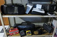 Wide shot of several radios and music players on metal shelves including a black toaster-style radio, portable units and boxed items