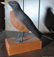 Front-side view of the full size robin figure mounted on a rectangular wooden base, showing detailed paint and texture on bird body and legs.