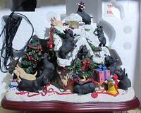 Front and top view of the Christmas doghouse figurine showing many Scottie dogs, presents, and greenery garlands on snow-covered roof.