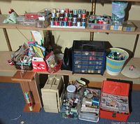 Wide angle photo showing entire sewing lot with multiple spools of thread, clips, needles, pins, containers, and other accessories on shelves and floor