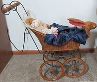 Side view of Victorian replica wicker bunny stroller with stuffed bunny and blue blanket inside.