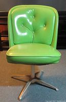 Front view of green mid century modern chair with tufted cushion and white base.