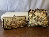Both vintage tapestry handbags showing different sizes, metal frames, chain handles, and classical romantic scenes embroidered in tapestry fabric