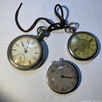 All three watches arranged on a white background showing dial faces and metal cases, one with leather string.
