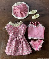 Pink Barbie 5-piece fashion set laid out on wooden surface showing front view.