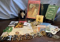 Overview of all items including booklets, rosaries, medals, holy cards and decorative artifacts arranged on table