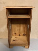 Full front view of the wooden nightstand showing the open cabinet space, fixed shelf inside, and heart-shaped cutouts on sides.