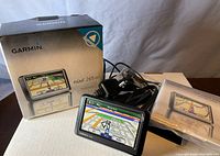 Lot contents including Garmin nüvi 265WT GPS, original box, instruction booklet, and cables.