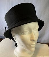 Front and side view of the black wool felt hat on a mannequin head showing the shape and basic design.