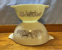 Side view of two stacked Pyrex mixing bowls showing mushroom pattern and speckled beige exterior.