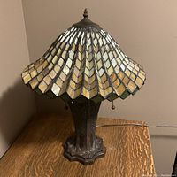 Full view of the lamp showing the metal base and Tiffany-style glass shade with light and dark yellow glass tiles.