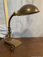 Side view of lamp showing flexible neck, dome shade, cast iron base, and ruler for scale at about 15 inches tall.