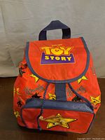 Front view of the red Toy Story backpack with logo and character star designs