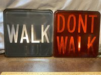 Both vintage Walk and Don't Walk heavy glass crosswalk plates side by side on a surface with a ruler for scale.