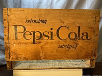 Side view showing 'refreshing Pepsi-Cola satisfying' black text on light wooden slats with reinforcement staples.