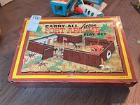 Image of Carry-All Action Fort Apache play set folded metal carrying case with vibrant color illustration on lid, showing signs of age and wear