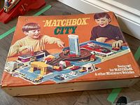 Top view of the Matchbox City carrying case showing the illustrated cover with children playing with miniature vehicles, buildings, and roads.