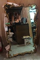 Full view of the large rectangular mirror with ornate gold frame showing reflective surface and frame details.