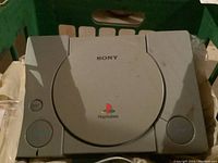 Top view of original Sony PlayStation console closed, showing the gray plastic body and PlayStation logo on the lid.