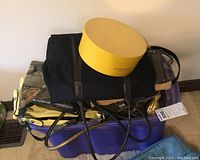 Multiple purses, wallets, and a black tote bag stacked on a purple storage bin