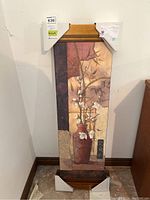 Full view of rectangular wall art with red vase and white flowers, framed in wood-toned frame with corner protectors.