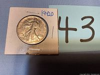 Front view of the 1942-D Walking Liberty half dollar coin in protective cardboard holder with handwritten date and mint mark.