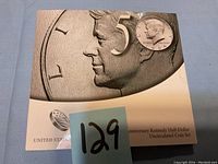 Close-up photo of the sealed 50th Anniversary Kennedy Half Dollar Uncirculated Coin Set packaging including embossed coin image and '50' anniversary mark.