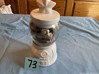 Front view of the ceramic gumball machine container filled with various small items