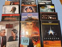 Photo of 11 DVD movies stacked showing titles including Vacation, Enemy at the Gates, The Village, Stargate and others