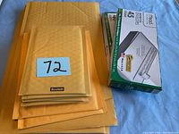 Stack of Scotch bubble mailer envelopes on top of larger manila envelopes next to box of Mead 45 clasp envelopes