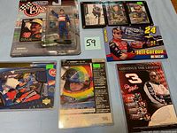 Photo showing the full lot of NASCAR memorabilia including a Jeff Gordon action figure in packaging and multiple racing trading cards.