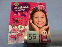 Front of the boxed DIY Headband Making Kit showing the brand Prettyate, over 50 pieces included, suitable for ages 5 and up, and an image of a girl wearing colorful headbands made from the kit.