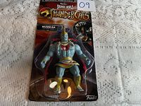 Front view of unopened Funko Thundercats MUMM-RA figurine in packaging on a textured cloth background.