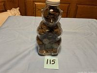 Front view of vintage glass bear jar filled with wheat pennies and 1940s nickels on a blue cloth surface.