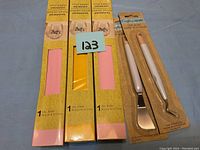 Three packages of vinyl paper in pink and yellow colors, and two vinyl crafting tools on a grey surface.