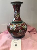 Front view showing floral decorations on red cloisonné vase and auction label.