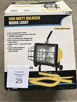 Photo of the box displaying product features including 500 Watt halogen bulb, vinyl-insulated lever handle, tempered UV safety glass, multi-position tilt control, outdoor rated power cord, and stand with secure footing.