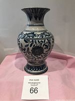 Front view of blue and white ceramic vase with floral and leaf patterns on bulbous body and flared top rim
