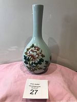 Full view of porcelain vase on pink cloth showing overall shape and color.