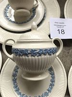 Close-up of sugar bowl with lid showing ribbed embossed white ceramic with blue floral band