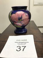 Full front view of William Moorcroft orchid cabinet vase with auction lot number card visible.