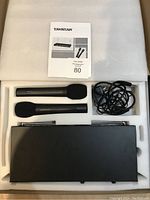 Takstar TG-700W wireless karaoke microphone set packed in foam, showing two microphones, receiver, cable, and manual