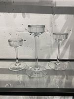 Three clear glass tealight holders shown in varying heights with transparent glass and round bases