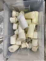 Bin of used white and cream pillar candles of various sizes.